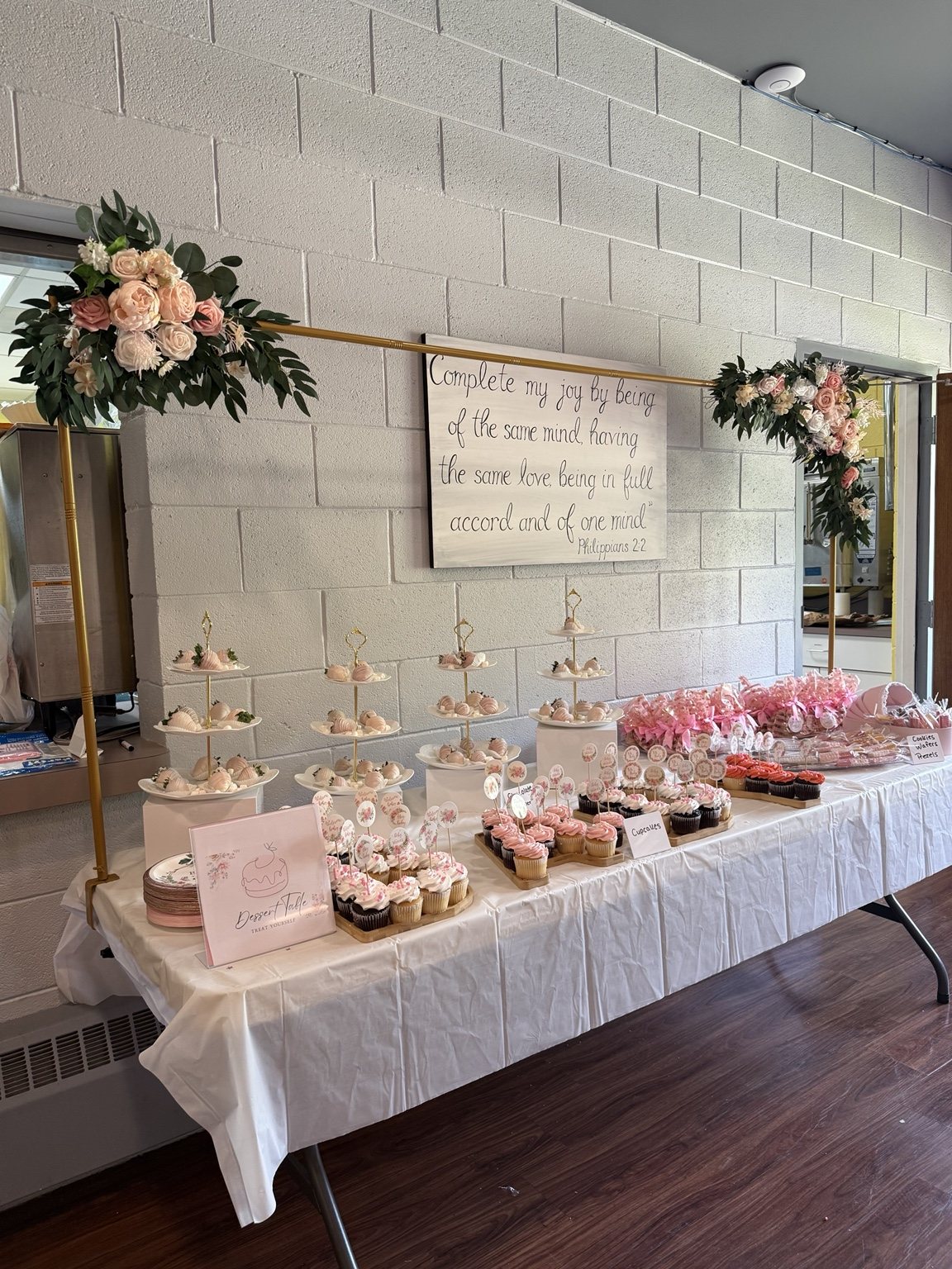 Blush pink styled dessert table with floral frame and custom treats